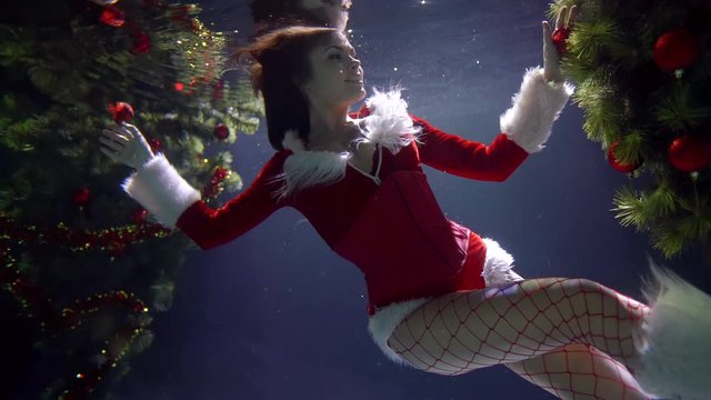 unusual Christmas underwater shot, sexy young woman dressed like Santa Claus is floating