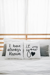 comfy wooden bed for couple decorated with "I have always known, It was you" heart pillow cosy bedroom at home valentines day, romantic date and holidays concept