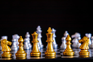 Selective focus leadership confrontation concept symbol represent by gold and silver chess board game between leadership stand in front of teams, business leadership strategy, and teamwork competition