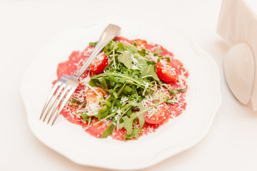 Arugula tomatoes on a white plate in a restaurant on a banquet table