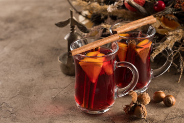 Two glasses of christmas mulled wine with oranges and spices on a textural background. Selective focus. Copy space.