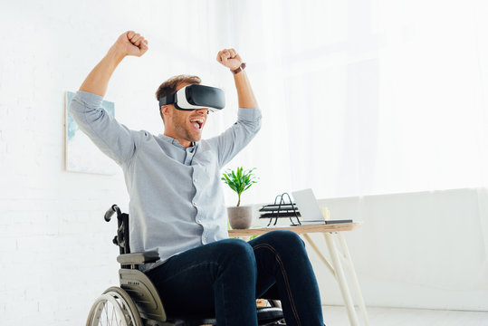 Cheerful man in wheelchair using virtual reality headset in living room