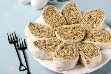 Lavash roll with chickpeas, mushrooms, carrots, onions and parsley on a light blue background,...