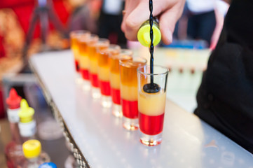 Red alcohol shot at a party is made by a bartender