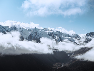 Beautiful landscape of snowy Caucasus mountains in the village of Dombay, Karachay-Cherkessia, Russia. Huge cold lonely snow cliffs high in the clouds,