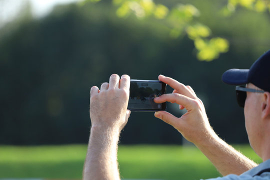 A man takes pictures on a competition phone. Free space, close-up, horizontal, rear view. Concept of hobby and technology.