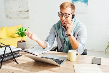 Smiling call center operator in headset working in living room