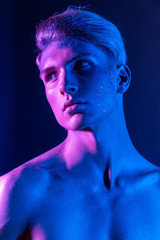 Handsome pumped up guy with naked torsos. Sports guy, attractive male body. Studio shooting with color filters