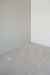 Corner of the room with gray and white walls and gray floor. 