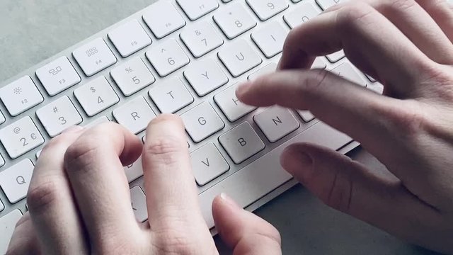 Hands typing on keyboard on office desk.