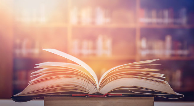 Book in library with old open textbook, stack piles of literature text archive on reading desk, and aisle of bookshelves in school study class room background for academic education learning concept