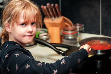 Fototapeta na wymiar Child in the kitchen at the stove while cooking