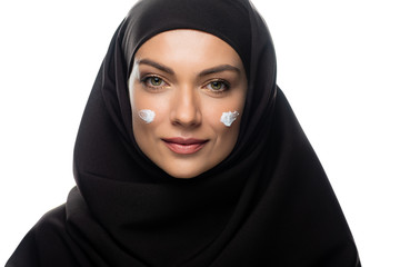 Naklejka premium young Muslim woman in hijab with cosmetic cream on chicks isolated on white