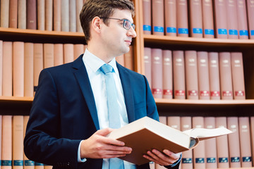 Anwalt in der Bibliothek seiner Kanzlei liest in der juristischen Fachliteratur nach 