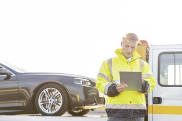 Tow truck driver writing report on clipboard