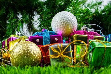 Christmas gift box and golf ball on grass