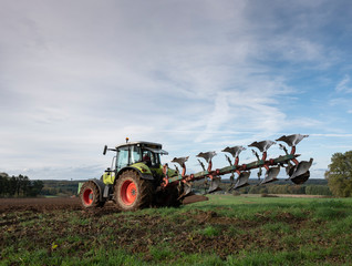 Fototapeta premium tractor and plow under blue sky on field in luxembourgh