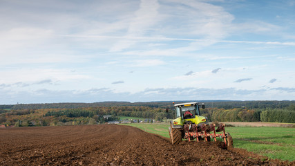tractor and plow under blue sky on field in luxembourgh