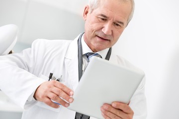 Dentist using digital tablet in clinic