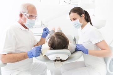 Doctor with assistant cleaning or pulling patient teeth in clinic