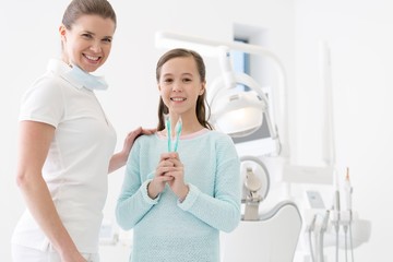 Fototapeta premium Child patient holding toothbrush with dentist in clinic