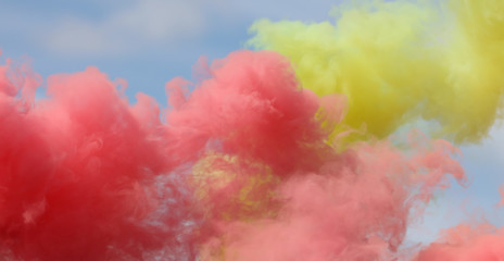 Fototapeta premium Red and yellow smoke on a blue sky