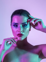 Gorgeous brunette model in the studio with color filters. Fashion, beauty, glow. Closeup side of a beautiful brunete woman in neon light purple and blue and green