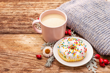 Hot coffee with a donut. Autumn drink for a good mood with plaid, fresh rose hips, leaves and flowers. Old wood plank background