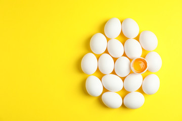 Flat lay composition with chicken eggs and half with yolk on color background, space for text