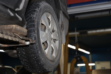 car on a lift in the garage for maintenance, wheel closeup