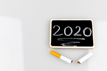 Noworocze postanowienie z rzuceniem palenia, papieros i tabliczka z rokiem © andsko