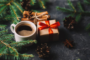 Obraz na płótnie Canvas Christmas background with tree branches, coffee and gift box on dark stone table