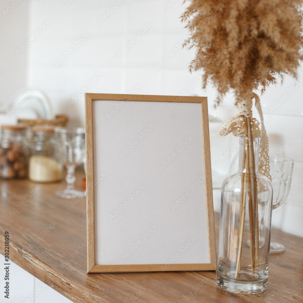 Wall mural wooden frame on the kitchen table in the interior.