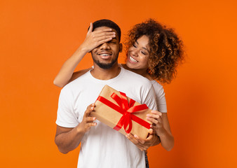 Beautiful girl covering her boyfriend eyes with present