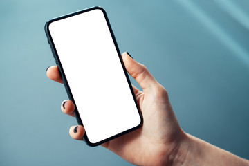 Mockup image of woman's hand holding thin bezels mobile phone with blank screen in glossy corporate environment - Image