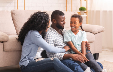 Black parents and daughter laughing, spending time together at home.