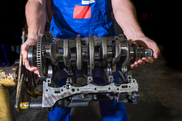 Auto mechanic working in a garage with a disassembled engine.
