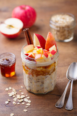 Overnight oats, bircher muesli with apple in glass jars on wooden background.