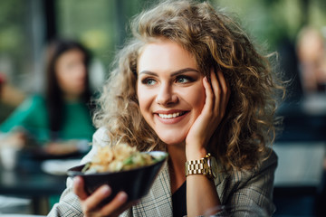 Blonde girl with long hair in a restaurant on ship. Girl tries salmon with rice. Girl eats appliances. The girl in the jacket after work eats.