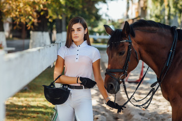 A young girl jockey with a horse in the park, hugged her face.