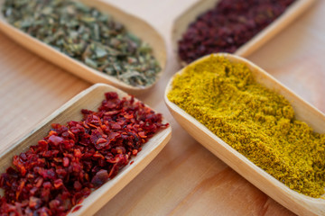 wooden spoons, different kinds of spices, pepper, turmeric, thyme and sumac on wooden background.Isolated background with copy space