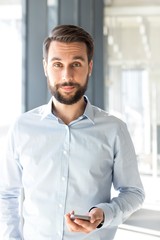 Businessman smiling while using smartphone in office