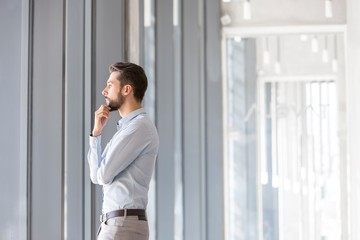 Fototapeta premium Young thoughtful businessman looking in to the window in office