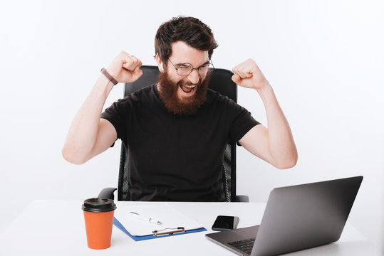vMan celebrating with fists up and looking at laptop
