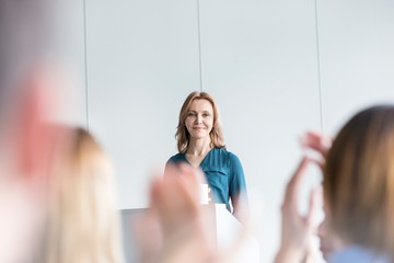 Business people applauding after businesswoman presentation in office