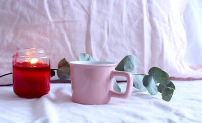 Cozy winter morning ,breakfast in bed .Romantic background with cup of coffee with candle and twig of eucalyptus . Soft photo. Greeting card style.