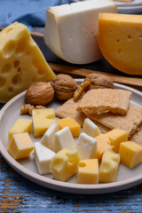 Tasty snacks, cheese blocks from Dutch yellow gouda and white goat hard cheeses and French holes cheese emmentaler