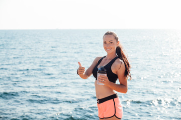 girl drinking water from a shaker after a workout on the beach