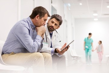 Doctor discussing medical result to patient with digital tablet in clinic