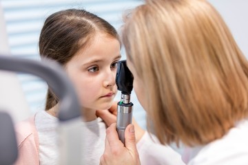 Doctor examining child patient's eye in clinic